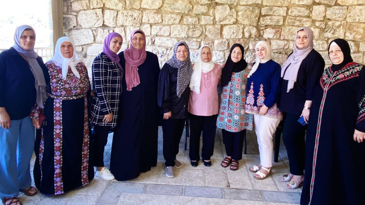 10 women from battir stoof against a stone wall background