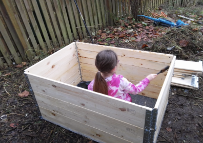 child in a compost bin in a community garden in a pink outfit in killingbeck orchard