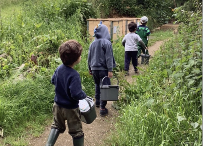kids composting 4 kids carrying caddies walking to compost bins